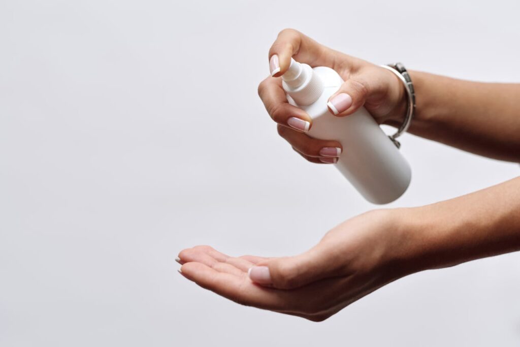 pexels photo 4177223 Close-up of hands applying sanitizer from a white spray bottle, showing hygiene care.