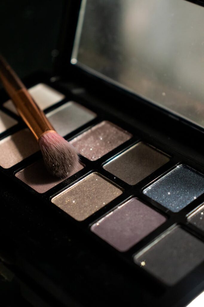 pexels photo 4702570 Detailed image of an eyeshadow palette with a makeup brush resting on it, showing various shades.
