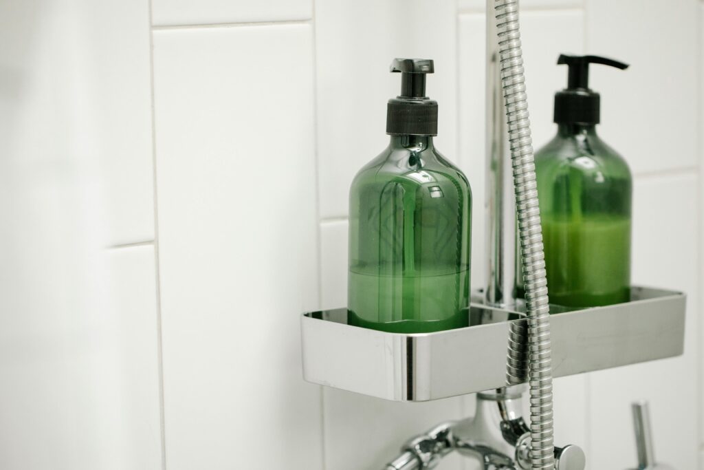 pexels photo 7262993 7262993 Green dispensers with body lotion on shelf on shower system in bathroom against tiled wall